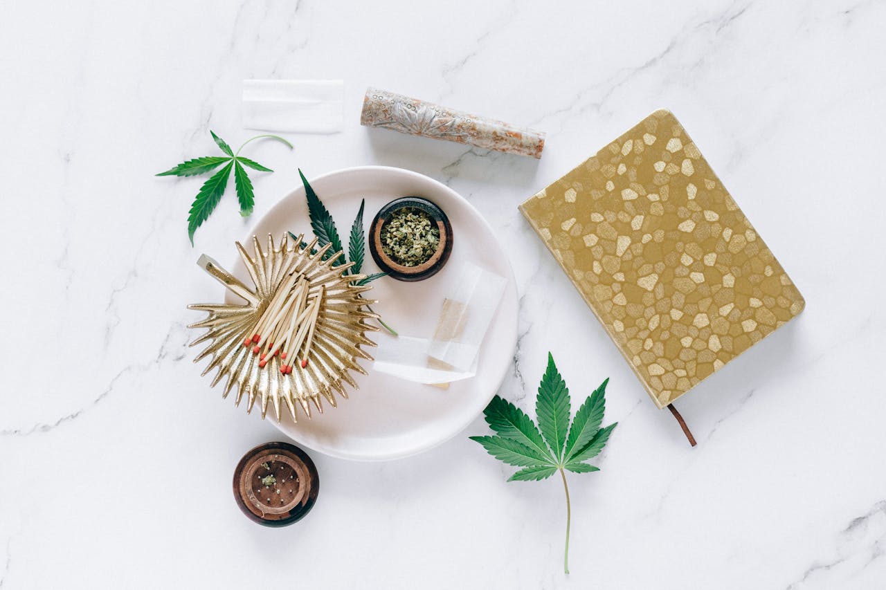 about-04 Cannabis leaves and related items neatly arranged on a marble tabletop, showcasing a lifestyle concept.